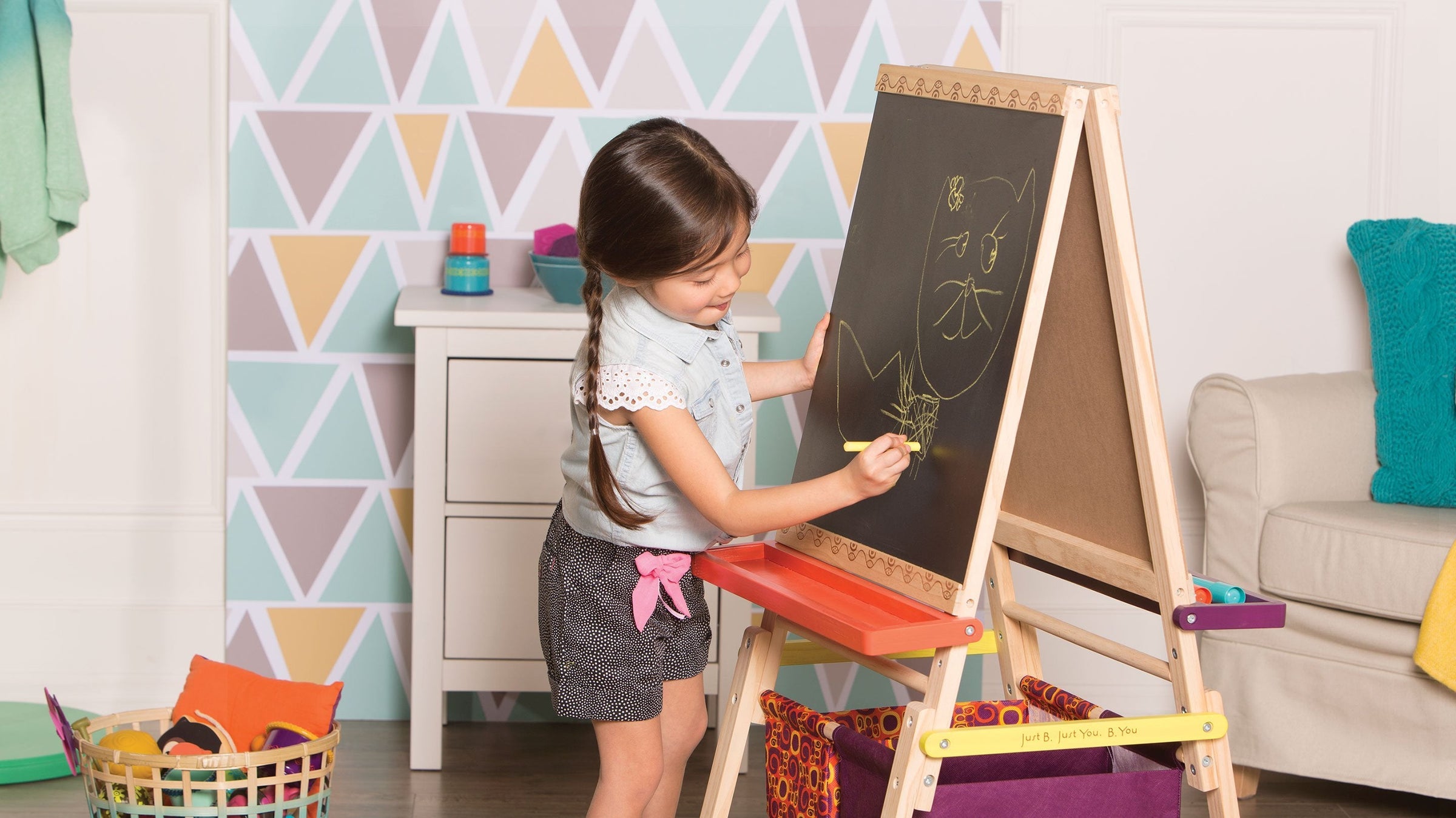A little girl drawing on a Chalk board